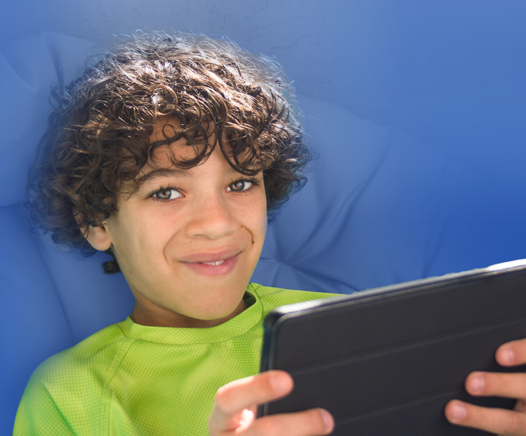 middle school aged boy reading at home on a tablet